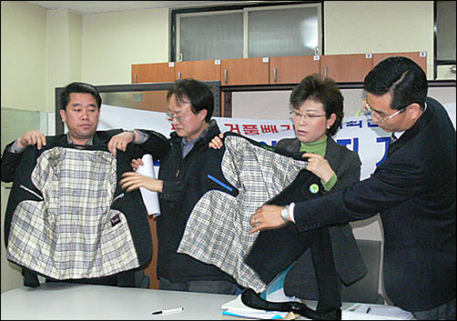 참교육학부모회 인천지부가 기자회견을 통해 한 중학교에서 공동구매한 교복제품과 대기업 제품을 보이며 가격 차이는 크나 품질에서 큰 차이가 없음을 설명하고 있다. 